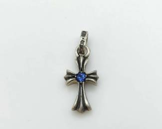 Iconic cross charm pendant crafted in solid sterling silver, featuring Chrome Hearts’ signature gothic cross silhouette accented by a vivid blue sapphire at the center. The sculptural form showcases bold contours and refined detailing, reflecting the brand’s distinctive rock-luxury aesthetic. A highly recognizable and collectible pendant suitable for wear on a chain or bracelet.