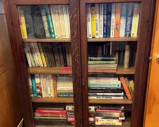 Oak bookcase filled with current in past titles and antique books