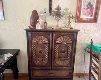 A vintage wooden armoire or door chest, characterized by its ornate Mediterranean or Spanish Revival style, and a collection of crosses on top