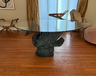 Round glass topped table with a ruffled edge and a black swan base
