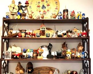Collection of Scandinavian-themed decorative items, including hand-carved wooden Viking figurines, painted wooden plated and model ships arranged on a dark wood wall shelf.
