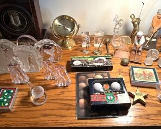 Collection of various golf-themed memorabilia features various crystal figurines of golfers and stylized sculptures.