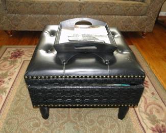 A black square ottoman with a black serving tray on top.  Everything nice and neat and in it's place