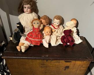 Vintage dolls sitting upon an antique chest.