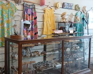 Vintage glass display case, women's dresses, hats, and accessories
