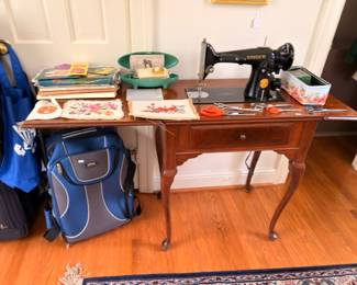Vintage Singer sewing machine in Queen Anne table with linens and luggage