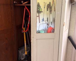 Vintage glass door cabinet full of yard tools and hoses
