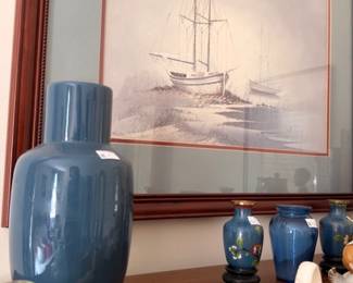 Blue pottery vase with framed nautical sailboat print