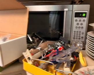 Stainless steel microwave with box of cords and kitchen gadgets