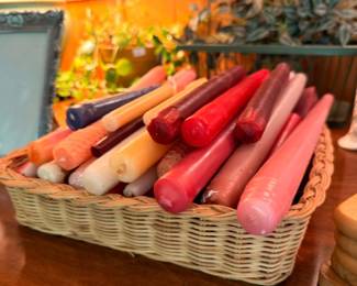 Large lot of taper candles in assorted colors in wicker basket