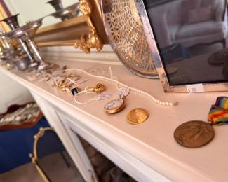 Pocket watches military medal and jewelry on mantel with silver tea service