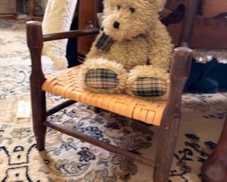 Antique child's rocking chair with woven seat and teddy bear