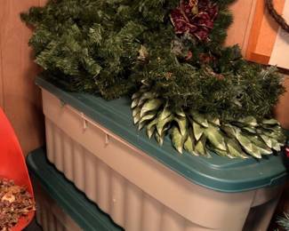 Storage totes with Christmas wreaths and artificial greenery