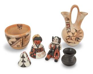 1389 A group of six Southwest Pueblo pottery items Six works:  Muriel Navasie (1954-1988, Hopi-Tewa) A polychrome wedding vase, mid/late 20th century Signed to underside: M. Navasie [spider cipher] With red and brown geometric motifs on a cream slip ground 6.625" H x 4" W x 3.375" D  Mary O. Chalan (b. 1939, Cochiti Pueblo) A polychrome storyteller, late 20th century Signed to underside: Mary O. Chalan / Cochiti / N. M. 3" H x 2" W x 2.75" D  Two Acoma Pueblo pottery bells, late 20th/early 21st century One signed: ACOMA / E. S. Comprising a figural three-color bell and a black on white slip bell 2 pieces Larger: 3.375" H x 2.5" Dia.  A diminutive blackware jar, mid-20th century Incised: RPL 2.125" H x 2.125" Dia.  A yellowware bowl, mid-20th century Unmarked 2.875" H x 3.875" Dia.  6 pieces total Estimate: $200 - $300