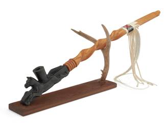 1320 Adam Fortunate Eagle (b. 1929, Chippewa) 'Medicine Horse Society Pipe," 1992 Signed and dated to the pipe end and the stand base: Fortunate Eagle / 1992 A carved steatite horse pipe bowl with a removable sumac stem decorated with beaded buckskin and horsehair, mounted on a custom cedar and deer antler stand 3 pieces Pipe bowl: 3.25" H x 2" W x 8.25" D; stem: 23.75" L x 1.5" Dia. Estimate: $500 - $700