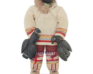 1147 Elisapee Inukpuk (b. 1938) & Charlie Inukpuk (b. 1941) An Inuit hunter figure with birds, circa 1962 Inukjuak, Nunavik, Canada Signature on base of doll not visible; Marked in ink to label on stone base: 9. / Woman artist / Inoucojuac [older name for Inukjuak, Nunavik, in the Nord-du-Québec] A hunter with carved stone head and hands, holding two carved stone birds, and dressed in an embroidered parka and boots 12" H x 6" W x 4" D Estimate: $200 - $400