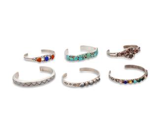 1368 A group of Southwest style stone set cuff bracelets Mid/late 20th century Each variously marked for maker and/or for sterling: AP / EA Getco Inc / MKL / [unknown cloud picto] Comprising six narrow set stone cuffs in various styles including channel inlay, row set, and cluster set, with various stones including turquoise, amber, lapis lazuli, shell, malachite, onyx, quartz, and hematite 6 pieces Largest: 6.375" total inner C x 0.25" H, gap: 1.25"; Smallest: 5.75" total inner C x 0.5" H, gap: 1" 97.9 grams gross Estimate: $200 - $400