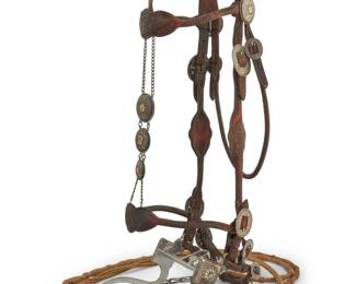 1100 An Edward H Bohlin Hollywood sterling silver mounted headstall bridle & reins 20th century; California Stamped to bit: Bohlinmade / Hollywood / Calif; further stamped to medallions: Hollywood Saddlery Ltd. A tooled brown leather fancy parade bridle with chased sterling silver and 9K gold concho medallions and buckles, including three faceplate conchos, one monogrammed SMD, as well as chased silver ornamentation to the Bohlin bit, and with narrow braided rawhide romal ortega-style reins with multiple buttons and a narrow leather popper end, with chain extensions. Headstall: 46.5" L; browband: 16" L; bit: 6" W; reins: 90" L total Estimate: $1,000 - $1,500