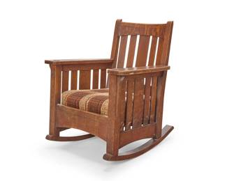 1175 A Limbert oak rocking chair Early 20th century Burned mark: Limbert's Arts and Crafts Furniture / Made in Grand Rapids and Holland With slatted back and corbeled flat armrests on slatted supports, the seat cushion upholstered in a later wool plaid fabric, raised on rockers 35.75" H x 30" W x 31.5" D Estimate: $500 - $700