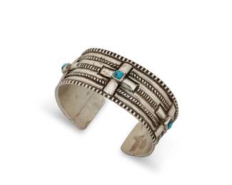 1342 A large Ernie Lister Navajo sterling silver cuff bracelet Ernie Lister (b. 1953, Diné) Late 20th/21st century Stamped: E Lister A chunky ridged silver cuff with three repoussé crosses each set with turquoise, and with stamped edging accents 8" total inner C x 1.25" H; gap: 1.125" 119.0 grams gross Estimate: $800 - $1,200
