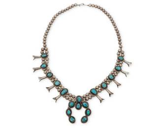 1330 A Southwest sterling silver and turquoise squash blossom necklace Mid/late 20th century Unmarked A chunky double strand necklace with ten graduated set turquoise blossoms, suspending a large central stone-set naja 27.5" L x 2.5" H 167.6 grams gross Estimate: $600 - $800