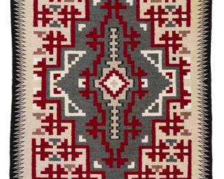 1220 A Navajo Ganado rug Late 20th century, Diné Woven in red, light and mid-grey, cream, and black wool featuring a central stepped diamond and complex stepped corners, with sawtooth borders to sides 52" H x 33" W Estimate: $500 - $700