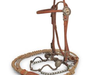 1102 An E.G. Field and California Classics leather and sterling silver headstall bridle & reins Early 21st century Bit stamped: E.G. Field / 2007; reins stamped: California Classics / Maker / Templeton, CA A 2007 narrow leather bridle with two sterling silver and 10K gold concho-style rosettes featuring bucking broncos, as well as sterling buckles and applied chased sterling ornamentation to the ornate E.G. Field bit, with braided rawhide romal ortega-style reins with multiple woven rawhide buttons and a heavy tooled leather popper end, with chain extensions. Headstall: 40" L; browband: 14.5" L; bit: 6" W; reins: 97" L total Estimate: $1,000 - $1,500