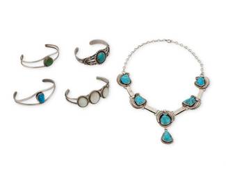 1333 A group of Southwest silver jewelry Mid/late 20th century Five works:  Jack & Mary Tom (b. 1948 & b. 20th century, Diné) A Navajo sterling silver and turquoise necklace Stamped: JT / Sterling / IHMJ With five set turquoise links with silver overlay accents and a central dangle 17" L x 2" H  A group of Southwest set stone cuff bracelets Two variously marked for maker and/or for sterling: MJ / [sign picto for Bell Trading Post] Comprising a Fred Harvey-style four wire stamped sterling silver cuff with central set turquoise cabochon and silver wire accents, as well as three further two-wire cuffs, including two with set turquoise, and one with three set mother of pearl plaques 4 pieces Largest: 6.5" total inner C x 1" H; Smallest: 6" total inner C x 1" H  5 pieces total 122.3 grams gross Estimate: $500 - $700