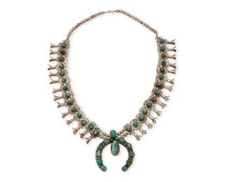 1329 A Southwest silver and turquoise 'box & bow' squash blossom necklace Mid-20th century Unmarked A double strand silver bead necklace of twenty-eight 'box and bow' blossoms, each with set nugget turquoise blossoms, suspending a large naja with twelve set nugget turquoise stones 22.5" L x 2.375" H 131.4 grams gross Estimate: $700 - $900
