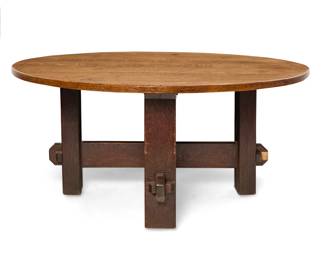 1171 A large Charles Stickley oak dining table Early 20th century Appears unmarked With a quarter sawn oak tabletop raised on exaggerated cross stretchers with large keyed tenon joinery 30" H x 65" Dia. Estimate: $2,000 - $4,000