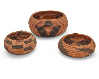1324 A group of diminutive Pomo baskets Early 20th century; Northern California Three coiled low basketry bowls, the largest with three geometric stylized floral motifs, and the smaller bowls with stepped radiating floral and geometric motifs 3 pieces Largest: 2.25" H x 5" Dia.; Smallest: 1.75" H x 3.5" Dia. Estimate: $500 - $700