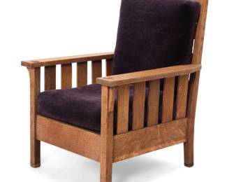 1077 A Gustav Stickley oak 'Morris' armchair, no. 332 1905-1912 With Craftsman Workshops applied label and joiner's compass burn mark The flat-arm chair with ladder back and slatted armrest supports, the seatback and seat cushions later upholstered in purple mohair 39.5" H x 28.75" W x 33" D Estimate: $1,500 - $2,000
