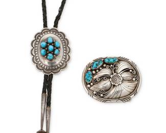 1337 A group of Southwest silver and turquoise jewelry Mid/late 20th century Buckle stamped: DC / Sterling Two works comprising an oval concho-style bolo with central cluster set turquoise and stamped edging accents, suspended from a braided black leather cord with silver cone tips, as well as an ornate sterling silver oval belt buckle with multiple applied silver floral, feather, and silver ball accents, with set nugget turquoise to one edge 2 pieces Bolo slide: 2.5" H x 2" W; cord: 39" L; Buckle: 2.375" H x 3" W; Belt ring: 1.875" 109.7 grams gross Estimate: $300 - $500