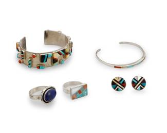 1406 A group of Southwest silver and stone set jewelry Late 20th century Cuff marked: AC [or G] / Sunburst / Sterling; earrings with label for Tracey Bowekaty, Zuni Five works comprising a textured sterling silver cuff bracelet with sculptural raised inlay in turquoise coral, and shell, and a small wire cuff with multistone inlay, together with two silver rings, one with a set lapis lazuli cabochon, and the other with turquoise, spiny oyster and shell inlay, as well as a pair of Zuni round disc earrings with multistone inlay 6 pieces Cuffs: 6.25" total inner C x 0.75" H, gap: 1" and 6.25" total inner C x 0.125" H, gap: 1"; each ring: size 9; earrings: 0.625" Dia. 67.1 grams gross Estimate: $200 - $400