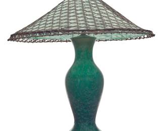 1278 An Arts & Crafts green glazed pottery table lamp Early 20th century Unmarked The ceramic vessel with crystalline glaze, mounted as a two-light lamp, surmounted by a woven bamboo and fabric shade, electrified Ceramic: 17.5" H x 7.25" Dia.; Lamp: 28.7" H; Shade: 9.5" H x 26" Dia. Estimate: $800 - $1,200