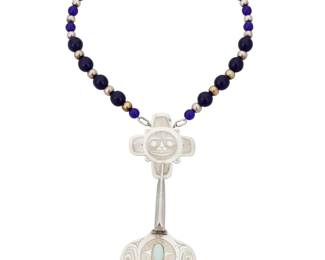 1142 Barry Lorne Wilson (b. 1952, Haisla) "Raven Carries the Light," 1990 A Haisla sterling silver and gemstone necklace Marked verso: BLW [conjoined] With elaborate incised sterling silver Northwest Coast stylized raven and sun pendant with central set opal, suspended from a strand of alternating blue Russian trade beads and silver beads, with a silver cone clasp 18" L x 6" H x 2.25" W 78.4 grams gross Estimate: $800 - $1,200