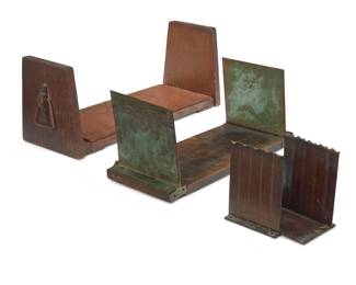1183 Two Arts & Crafts book stands and a pair of Roycroft bookends Early 20th century Each bookend impressed with Roycroft orb Comprising a wood stand with opposed handles, a stand with wood base and silver overlay copper ends, and a pair of Roycroft hammered copper bookends 4 pieces Largest: 6.75" H x 18.75" W x 6.25" D; Each bookend: 5.125" H x 3.75" W x 3.25" D Estimate: $300 - $500