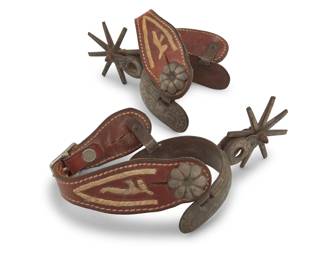 1112 A pair of silver overlay spurs 20th century The wrought iron spurs with inlaid silver bands and tracery motifs to outer heel band, shanks, outer strap buttons, and rowels, each spur with a circular shank issuing eight-point rowels, and each with a shaped embroidered leather strap 2 pieces Each: inner heel band: 3.5" W ; heel depth: 3.75" D; shank: 1.875" L; rowels: 3" Dia. Estimate: $300 - $500