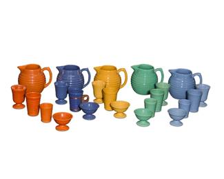 1269 A group of Bauer glazed pottery ringware table items Circa 1930s Comprising 5 taller cups (one with a copper holder and wood handle), 3 smaller cups, 5 footed cups, 5 footed bowls, and 5 pitchers, all forms but the smaller cups represented in five classic Bauer colors 23 pieces Each pitcher: 6.625" H x 8.25" W x 6.625" D; Each footed cup: 4.625" H x 3.5" Dia. Estimate: $500 - $700