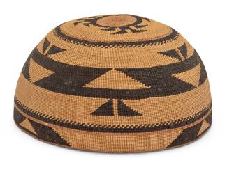 1323 A polychrome Hupa/Yurok/Karuk basketry hat Early/mid-20th century; Northern California A twined hat with imbricated triangular and hooked banding to sides and clusters of triangular 'foot' motifs to crown 3.5" H x 6.5" W x 6.25" D Estimate: $500 - $700