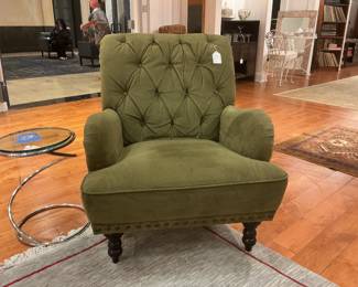 Elegant seating pairing featuring a classic tufted armchair in sage green velvet with brass nailhead trim and turned espresso legs. Paired with a contemporary minimalist side table featuring a circular glass top and a sculptural chrome spiral base.