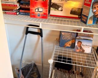 DVDs, VHS tapes, board games, books on wire storage cart, media collection lot