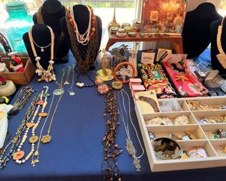 Costume jewelry table with beaded necklaces, brooches, and vintage accessories