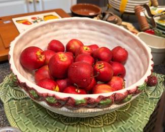 Decorative faux red apples in ceramic bowl, green leaf plate, kitchen table centerpiece