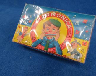 Lot 76. Toy harmonica box with contents. This came to us wrapped and we have not unwrapped it. It feels and sounds like there is one thing in the box.
