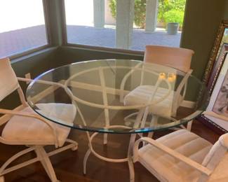 Round Metal And Glass Dining Table With Three Swivel Chairs On Wheels