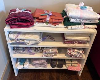 White shelf with folded table linens and fabric