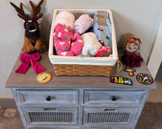 Weathered grey dresser with wicker drawers, topped with stuffed animals