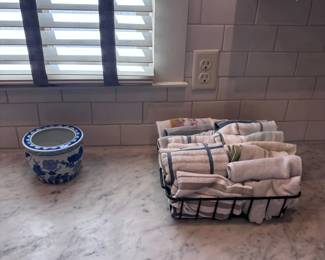 Blue and white porcelain planter and woven basket of towels