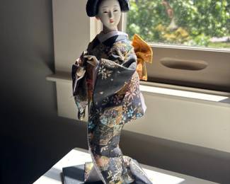 Japanese geisha doll in kimono on wooden stand